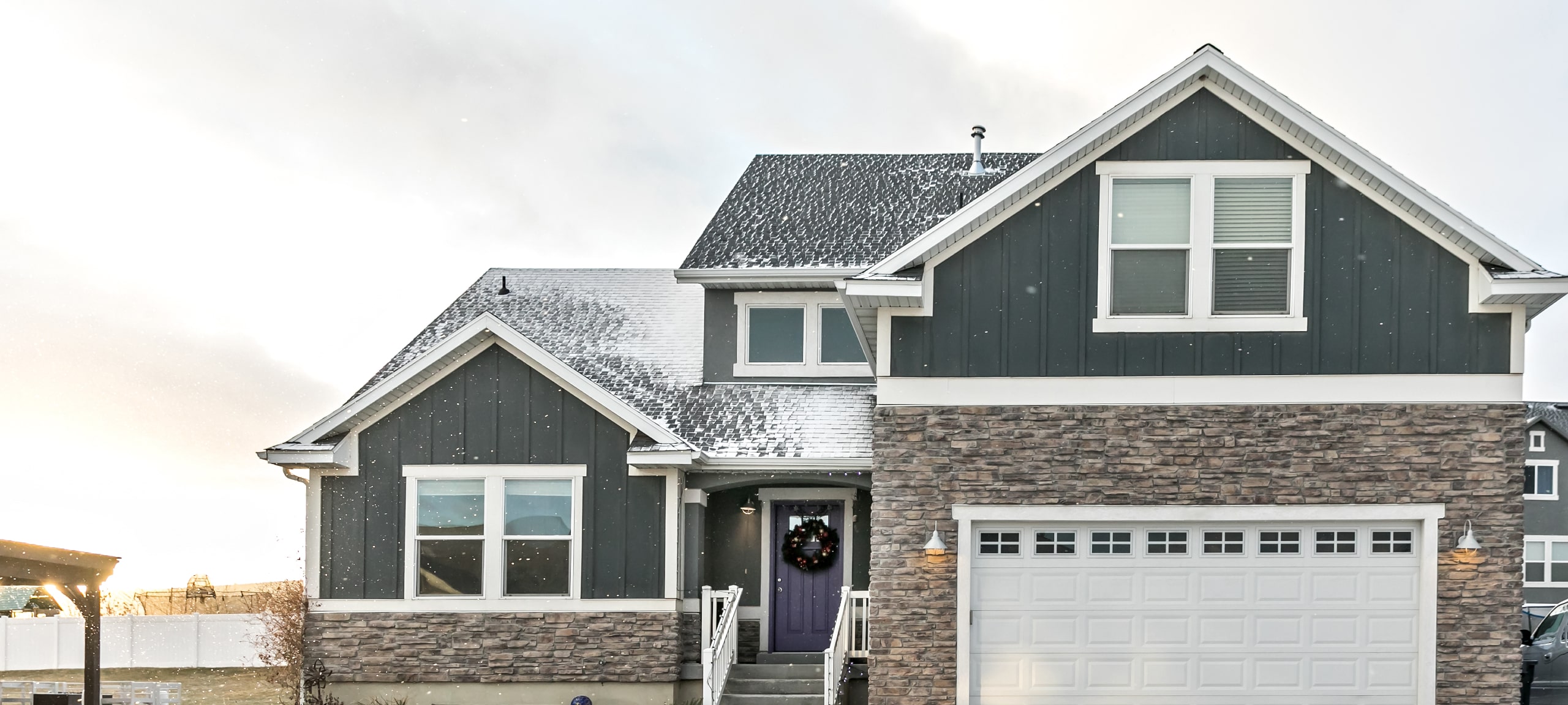 Suburban Craftsman style home with gray siding and stone in winter